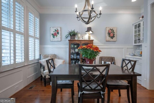 dining space with dark wood-type flooring, a notable chandelier, and ornamental molding