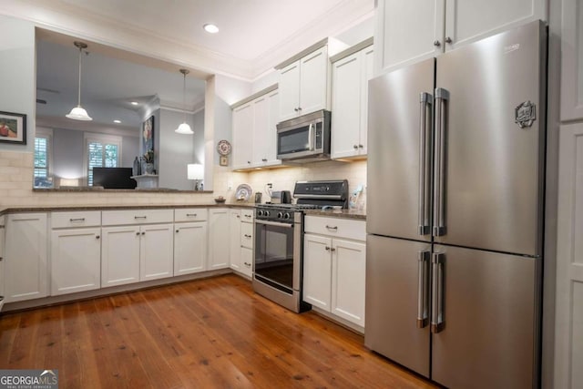 kitchen featuring white cabinets, hanging light fixtures, hardwood / wood-style flooring, crown molding, and stainless steel appliances