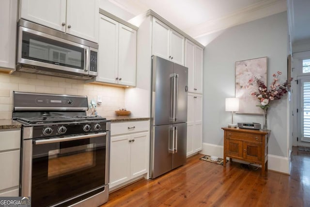 kitchen with appliances with stainless steel finishes, white cabinetry, a healthy amount of sunlight, and dark wood-type flooring