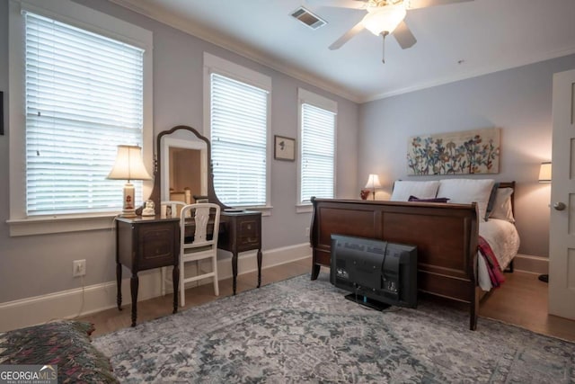 bedroom featuring multiple windows, ceiling fan, wood-type flooring, and ornamental molding