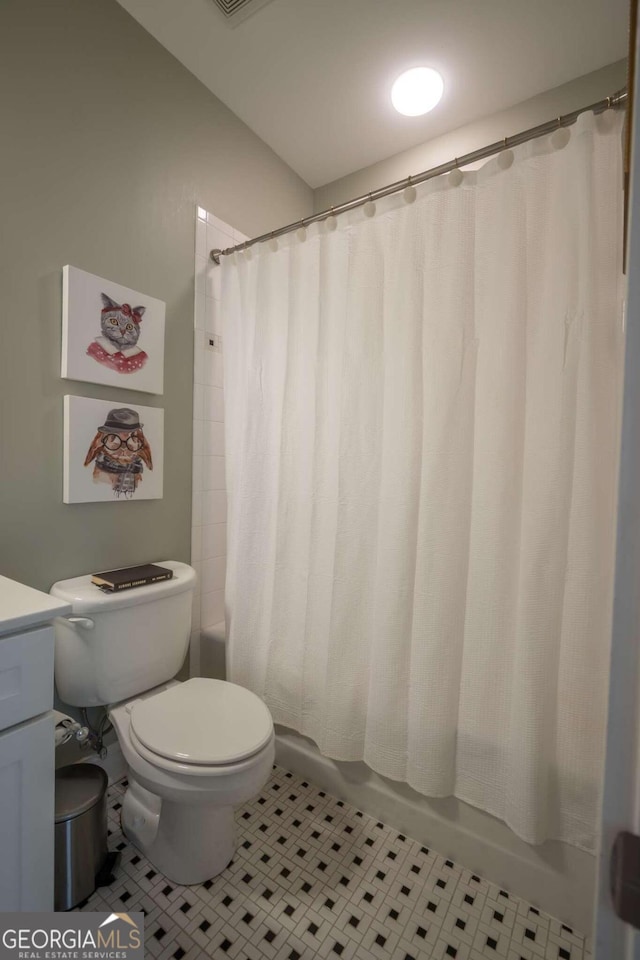 full bathroom featuring tile patterned flooring, toilet, shower / bath combo with shower curtain, and vanity