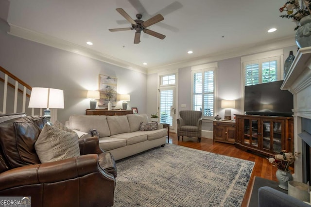 living room with dark wood-type flooring, ceiling fan, and ornamental molding