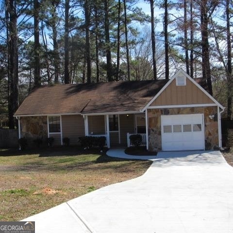 single story home featuring a front lawn, covered porch, and a garage