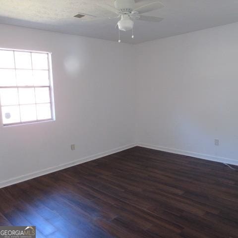 empty room with ceiling fan and dark hardwood / wood-style flooring