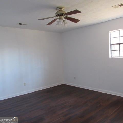 unfurnished room featuring dark wood-type flooring and ceiling fan