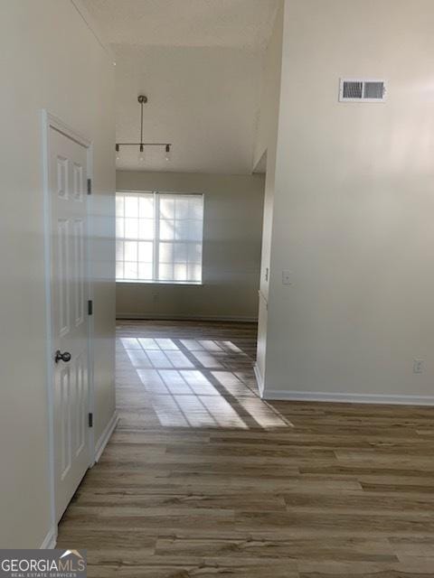 hall with a high ceiling and hardwood / wood-style floors