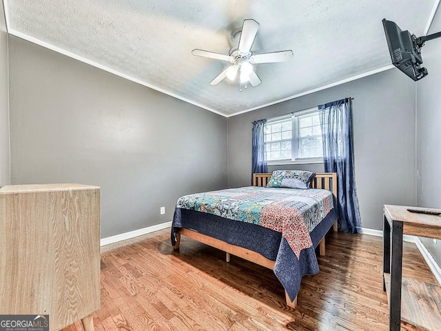 bedroom featuring ceiling fan, ornamental molding, and wood-type flooring