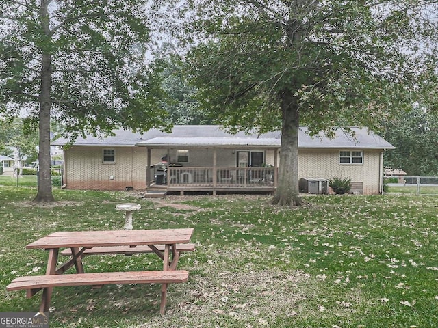 rear view of house with cooling unit, a yard, and a wooden deck