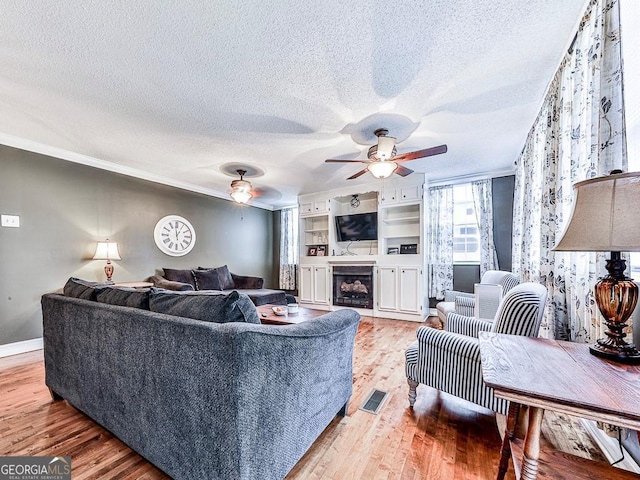 living room with ceiling fan, a textured ceiling, and light hardwood / wood-style flooring