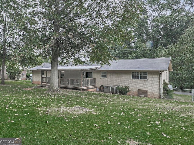 rear view of house with a lawn, a wooden deck, and cooling unit