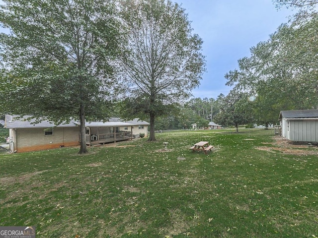 view of yard featuring a wooden deck and a shed