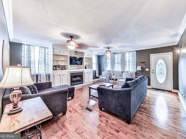 living room featuring a textured ceiling, crown molding, ceiling fan, and hardwood / wood-style flooring