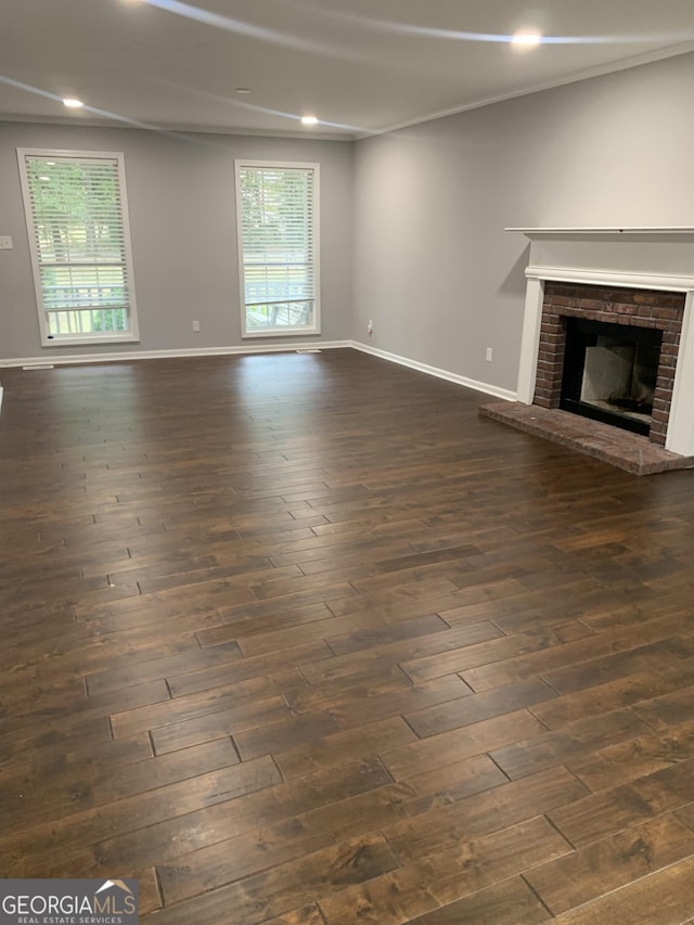 unfurnished living room with dark hardwood / wood-style flooring and a brick fireplace