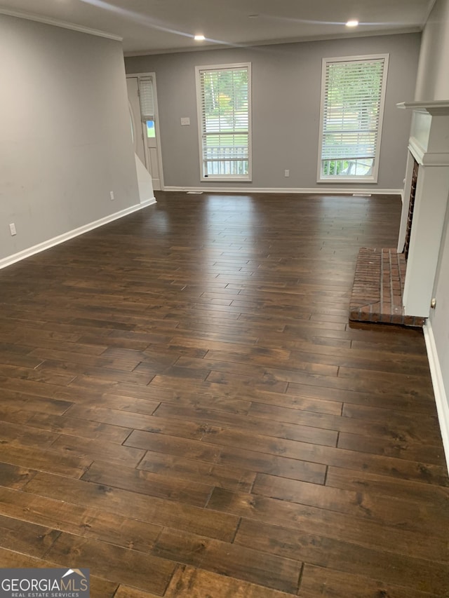 unfurnished living room with dark hardwood / wood-style floors, a brick fireplace, and ornamental molding