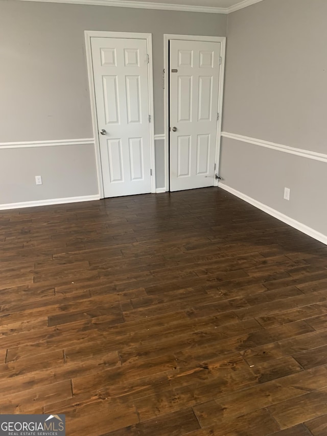 unfurnished bedroom featuring ornamental molding and dark wood-type flooring