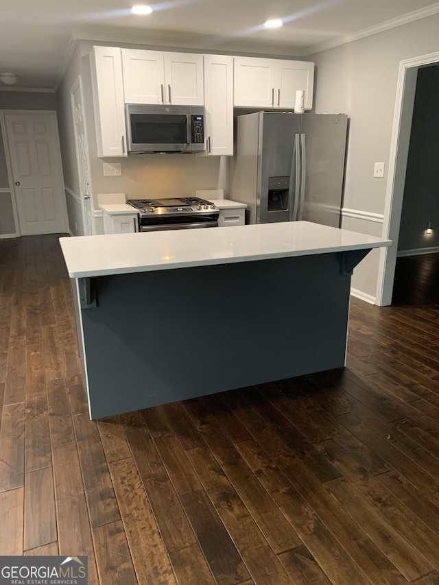 kitchen featuring appliances with stainless steel finishes, dark hardwood / wood-style flooring, a center island, and white cabinetry