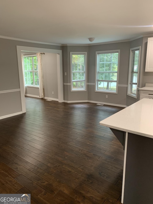 unfurnished living room featuring plenty of natural light, crown molding, and dark wood-type flooring