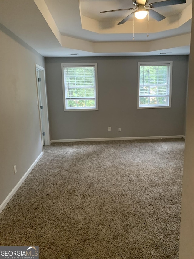 unfurnished room featuring ceiling fan, carpet floors, and a tray ceiling