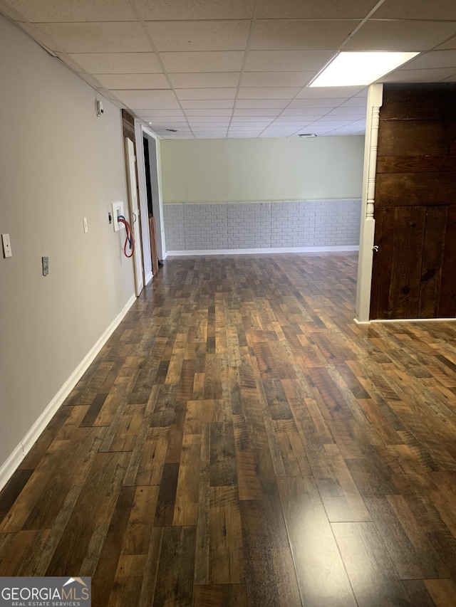 spare room with a drop ceiling and dark wood-type flooring