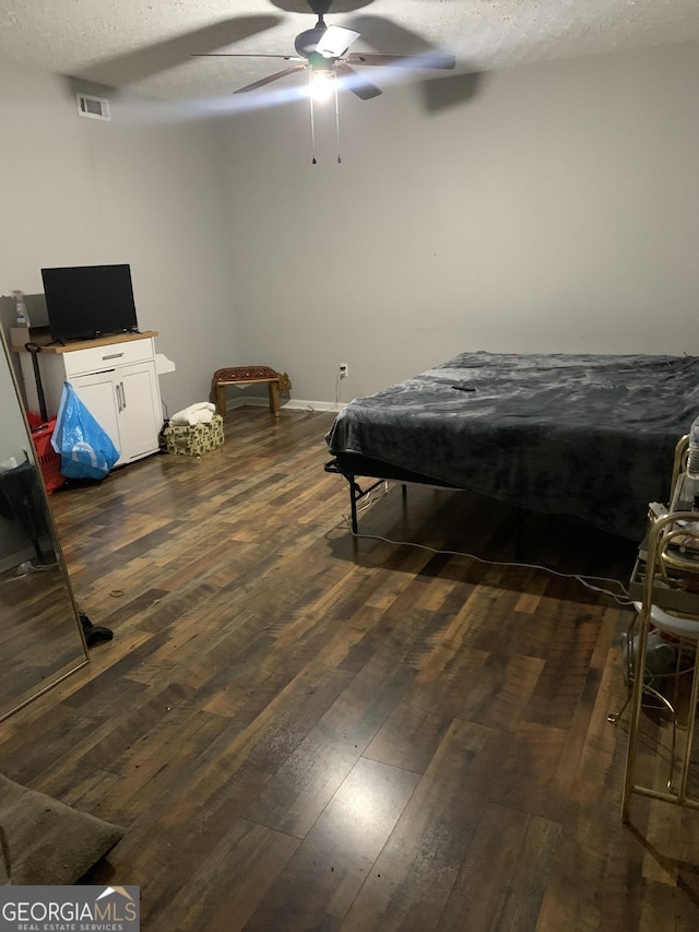 bedroom featuring ceiling fan, dark hardwood / wood-style flooring, and a textured ceiling