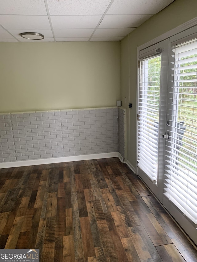 spare room featuring a paneled ceiling and dark hardwood / wood-style floors