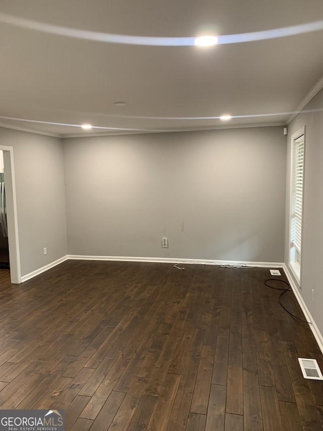 empty room featuring dark hardwood / wood-style flooring and ornamental molding