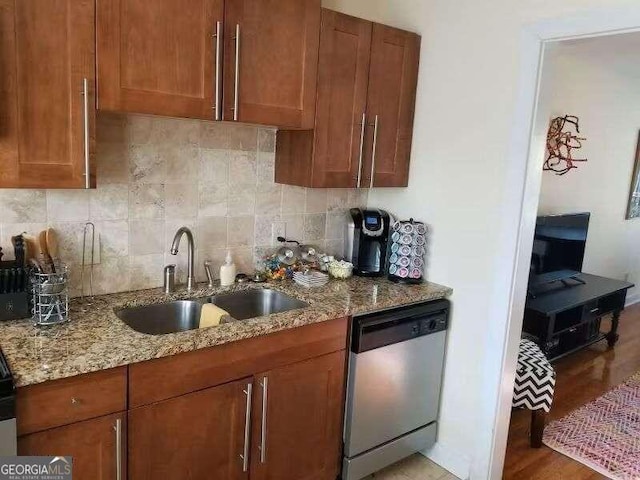 kitchen featuring light hardwood / wood-style flooring, stainless steel dishwasher, sink, and decorative backsplash