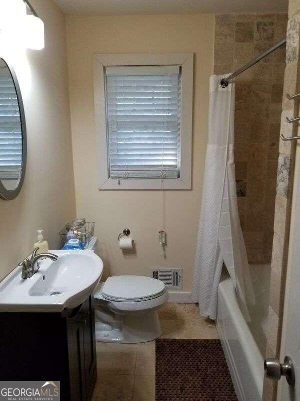 full bathroom featuring shower / bathtub combination with curtain, tile patterned flooring, toilet, and vanity