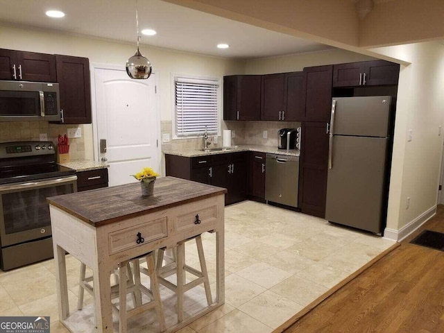 kitchen with dark brown cabinets, light hardwood / wood-style flooring, stainless steel appliances, and sink