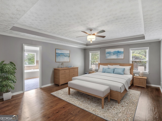 bedroom with a tray ceiling, ceiling fan, crown molding, and ensuite bathroom