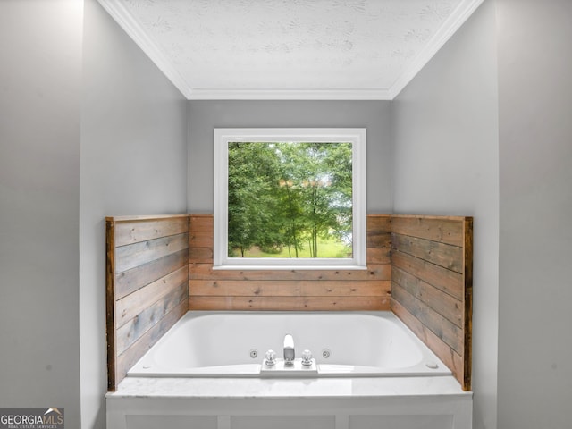 bathroom with a bath, a textured ceiling, and ornamental molding