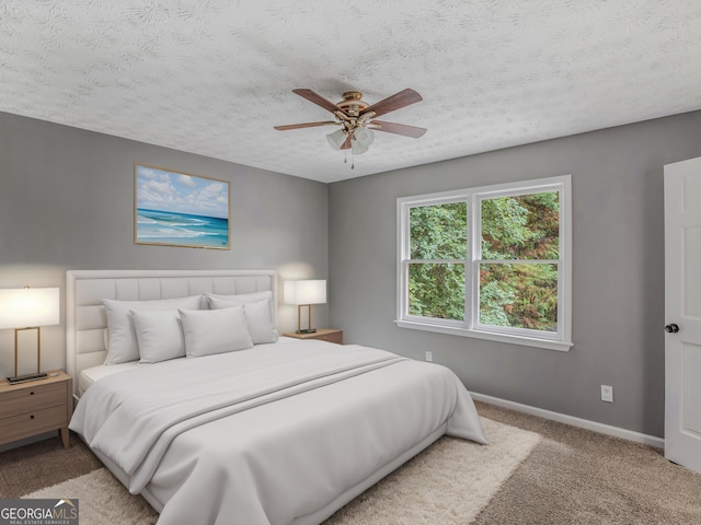 carpeted bedroom with ceiling fan and a textured ceiling