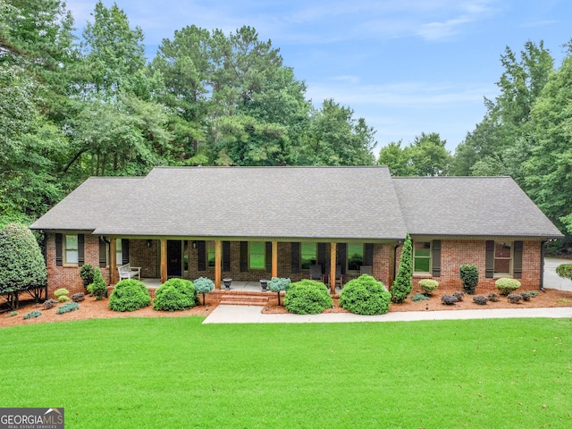 ranch-style home featuring covered porch and a front lawn