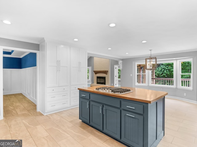 kitchen with wooden counters, ornamental molding, decorative light fixtures, white cabinets, and stainless steel gas stovetop