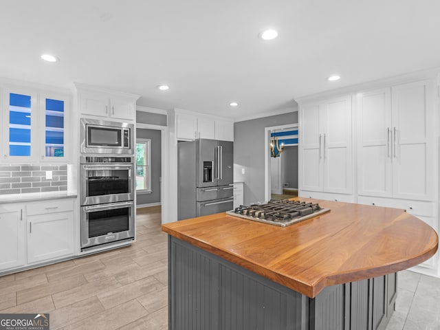 kitchen featuring decorative backsplash, white cabinetry, ornamental molding, and appliances with stainless steel finishes