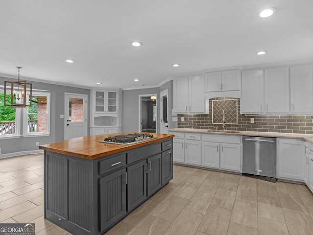 kitchen featuring white cabinetry, stainless steel appliances, butcher block countertops, a kitchen island, and ornamental molding