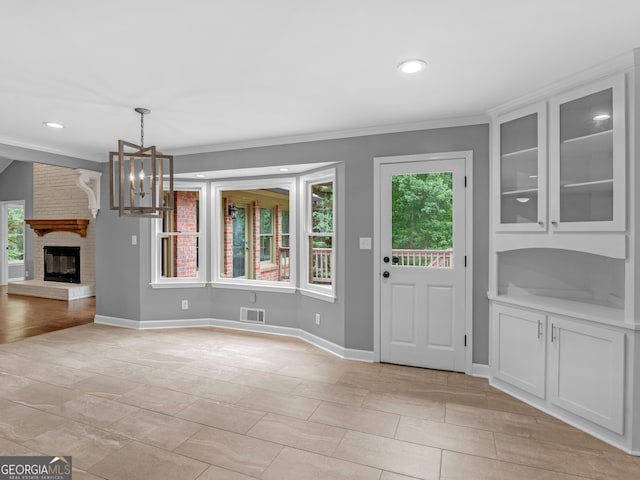 interior space with a healthy amount of sunlight, ornamental molding, a fireplace, and an inviting chandelier