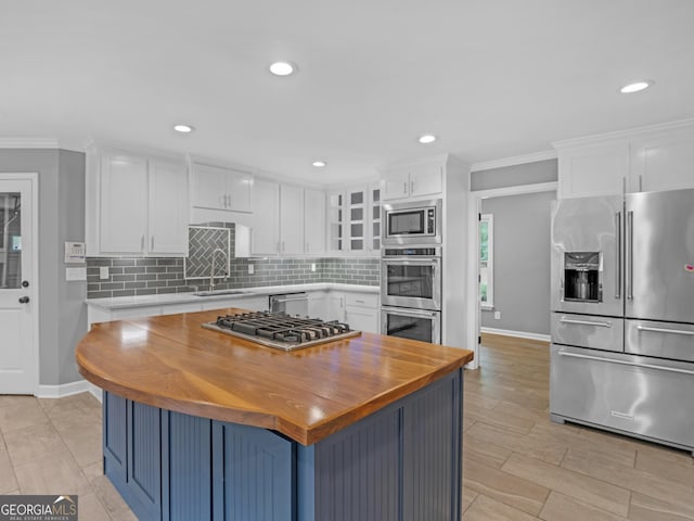 kitchen with white cabinets, ornamental molding, tasteful backsplash, a kitchen island, and stainless steel appliances