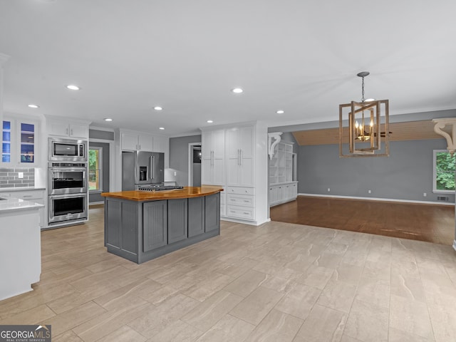 kitchen featuring white cabinetry, stainless steel appliances, wood counters, a notable chandelier, and a kitchen island