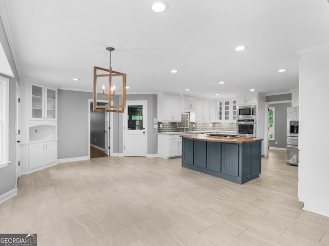 kitchen featuring butcher block counters, white cabinetry, stainless steel appliances, pendant lighting, and a kitchen island