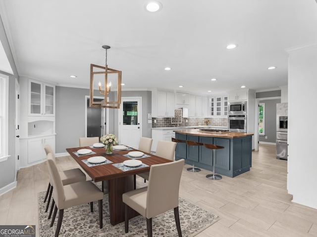 dining space featuring light hardwood / wood-style floors, sink, crown molding, and an inviting chandelier