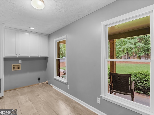 washroom featuring plenty of natural light, cabinets, a textured ceiling, and washer hookup