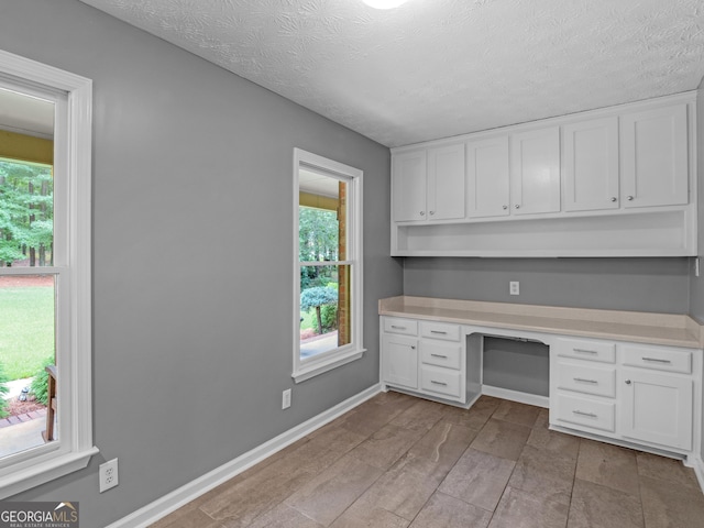 unfurnished office featuring built in desk and a textured ceiling