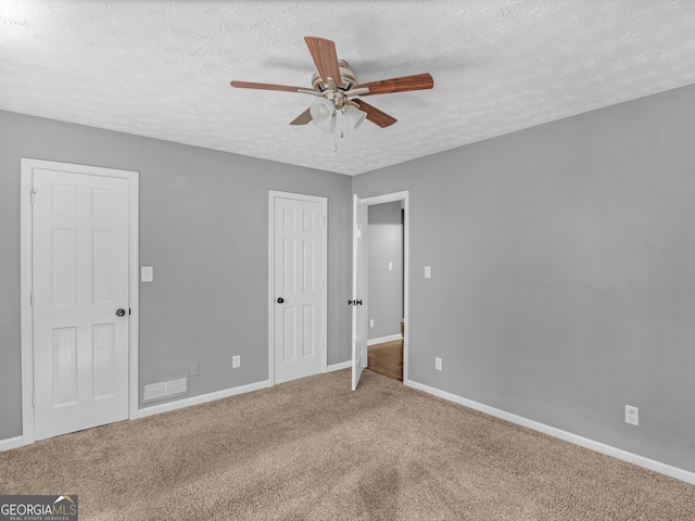 unfurnished bedroom with carpet flooring, ceiling fan, and a textured ceiling