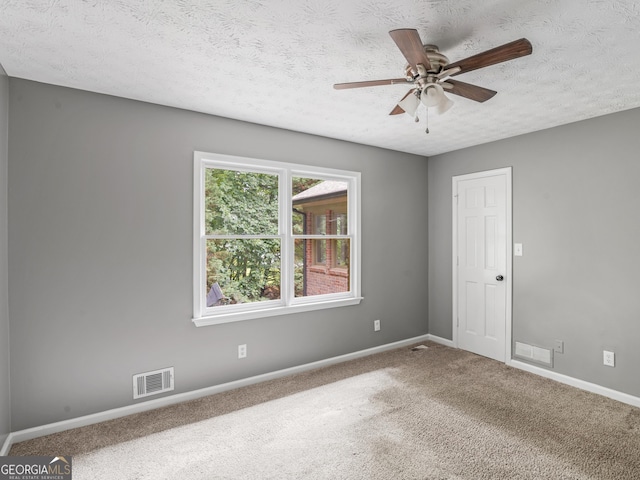 carpeted spare room featuring ceiling fan and a textured ceiling