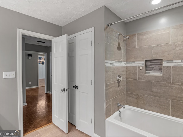 bathroom featuring tile patterned floors, tiled shower / bath combo, and a textured ceiling