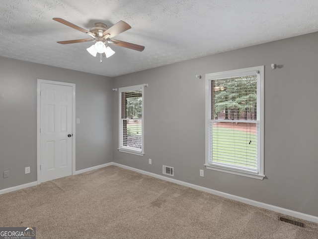 empty room featuring ceiling fan, a healthy amount of sunlight, carpet floors, and a textured ceiling