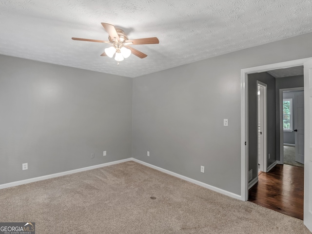 unfurnished room with ceiling fan, a textured ceiling, and dark colored carpet