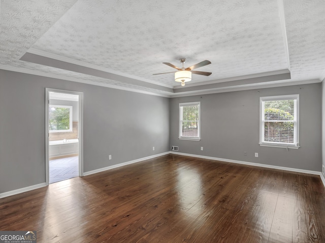 unfurnished room with a tray ceiling, ceiling fan, dark hardwood / wood-style flooring, and ornamental molding