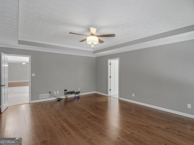 spare room with a raised ceiling, dark hardwood / wood-style floors, ceiling fan, ornamental molding, and a textured ceiling